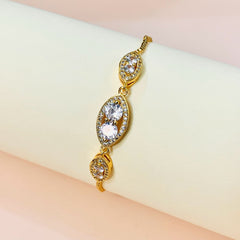 Gold bracelet with clear stones on a soft pink background