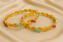 Pair of gold braided bracelets with colorful beads on a beige fabric background