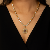 Gold necklace with a central gemstone on a black background