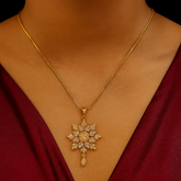 Gold necklace with a snowflake pendant on a person wearing a red garment.