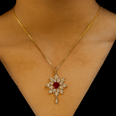 Gold necklace with a red gemstone pendant on a person's neck against a black background