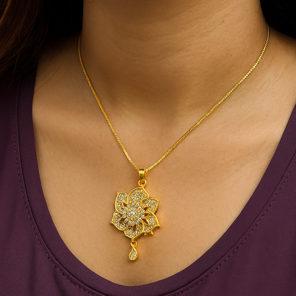 Gold necklace with a floral pendant on a person wearing a purple top.