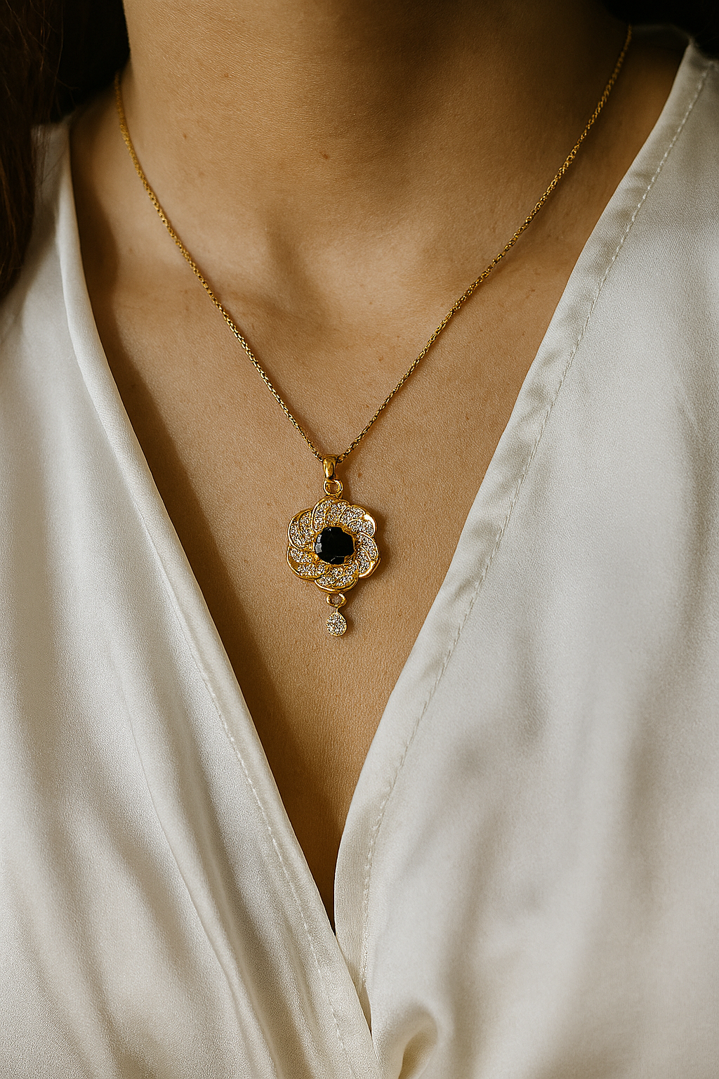 Gold necklace with a blue gemstone pendant on a white blouse