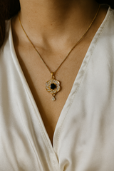 Gold necklace with a blue gemstone pendant on a white blouse