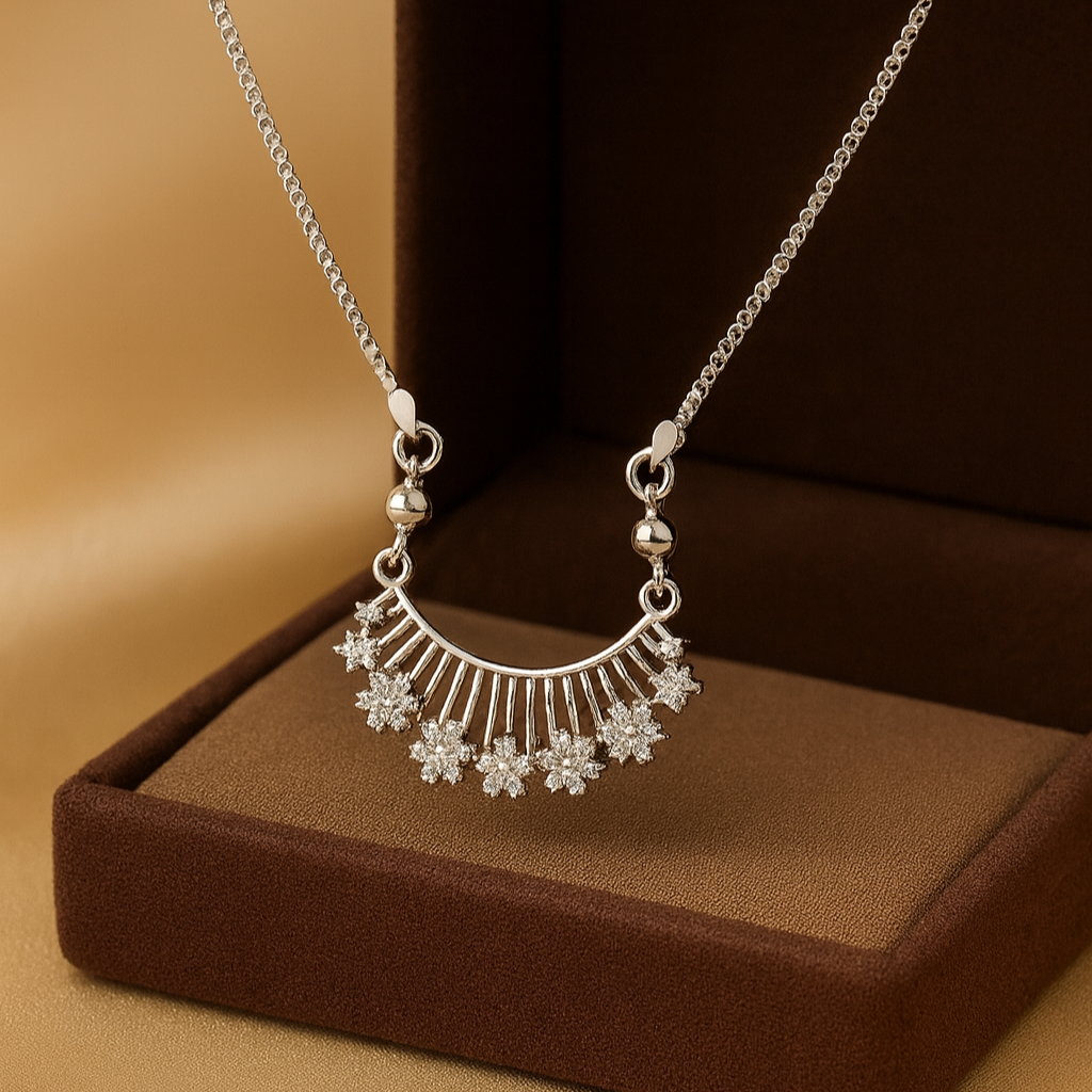 Silver necklace with a floral pendant on a brown cushion