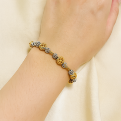 Hand wearing a gold bracelet with interlocking rings on a beige fabric background