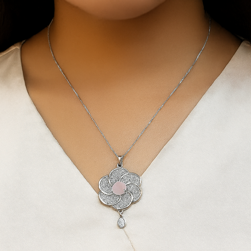 Silver necklace with a floral pendant on a person wearing a beige top.
